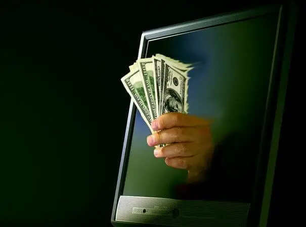Image of hand with money through laptop online gambling laws USA